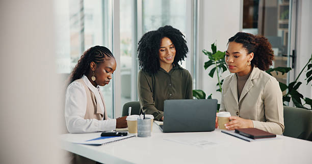 Three women discussing investments around a laptop in a bright office